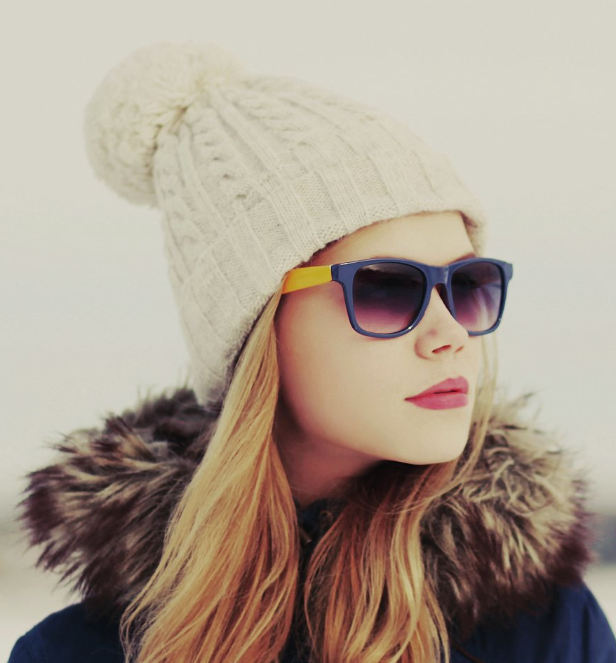 A woman wearing sunglasses and a beanie with a fur hood