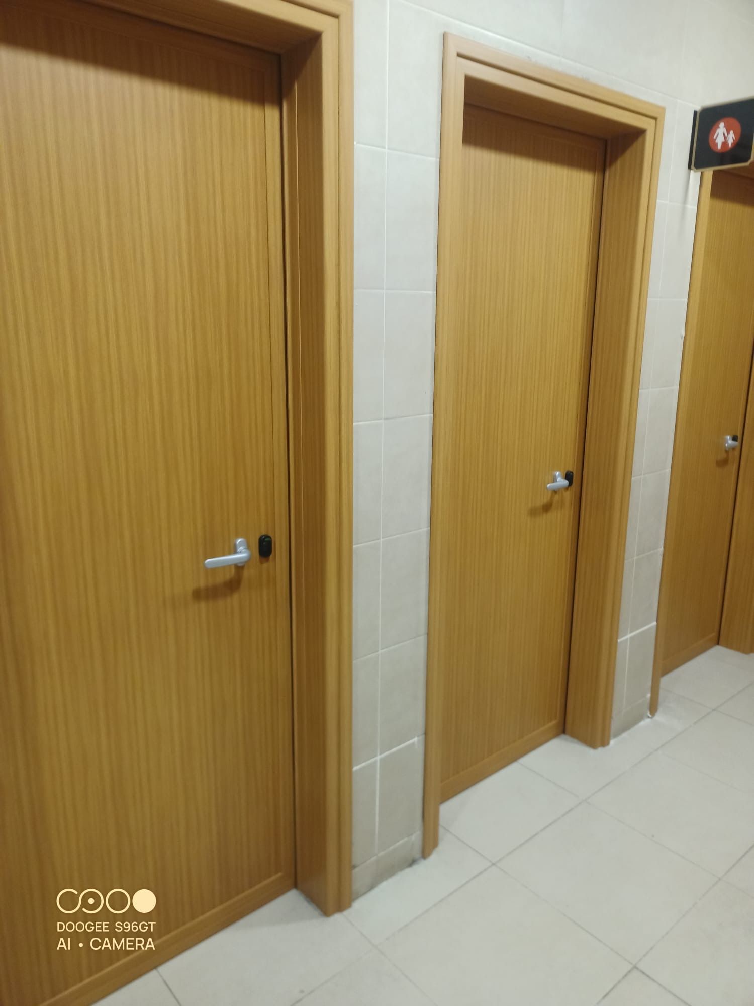 Tre porte di legno in un corridoio beige, viste da un'angolazione particolare.