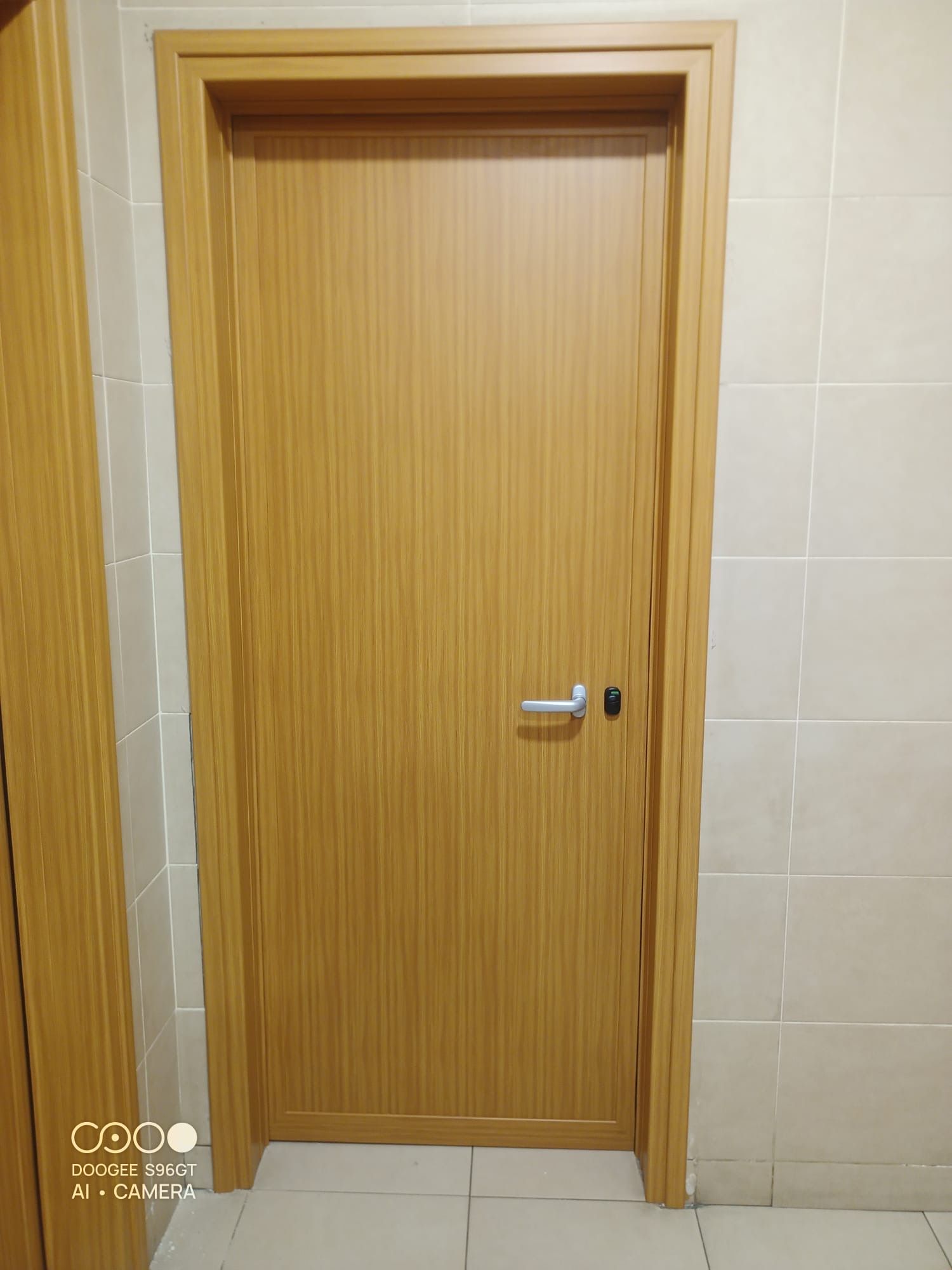 Porta in legno con maniglia argentata in un corridoio piastrellato beige