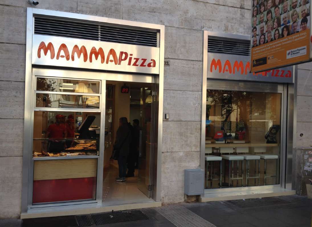 La vetrina di MAMMAPizza, con ingresso aperto e ampie finestre, si affaccia su una stretta via cittadina.