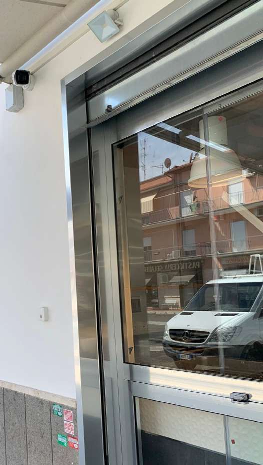 L'ingresso del negozio, con una vetrina riflettente, mostra un furgone bianco parcheggiato all'esterno.