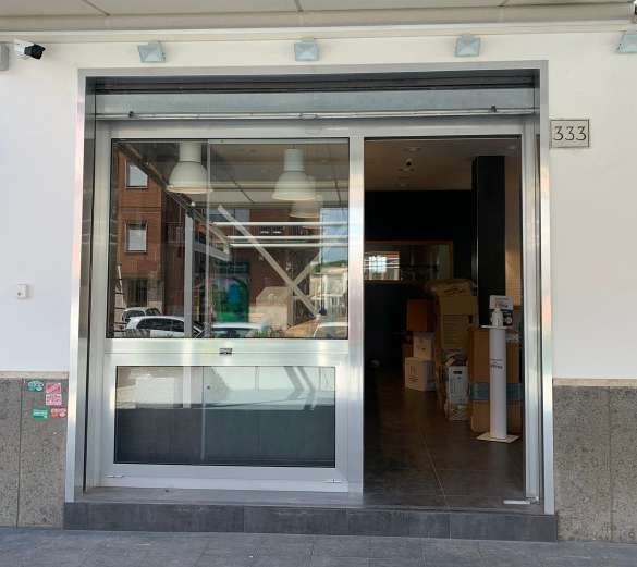 Ingresso con vetrina in vetro, porta scorrevole aperta e scatole a vista all'interno, numero 533 sopra la porta.