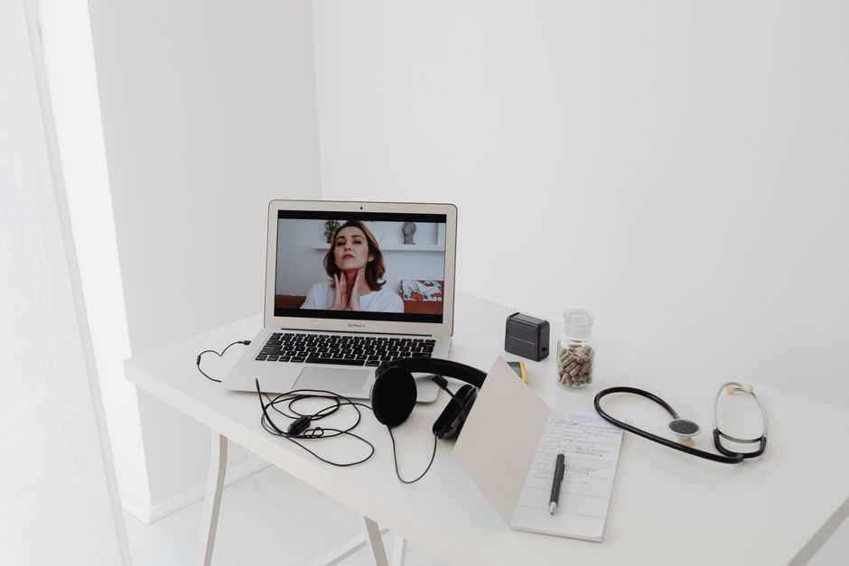 Minimalist laptop, headphones, and small globe representing a telehealth practice serving multiple states