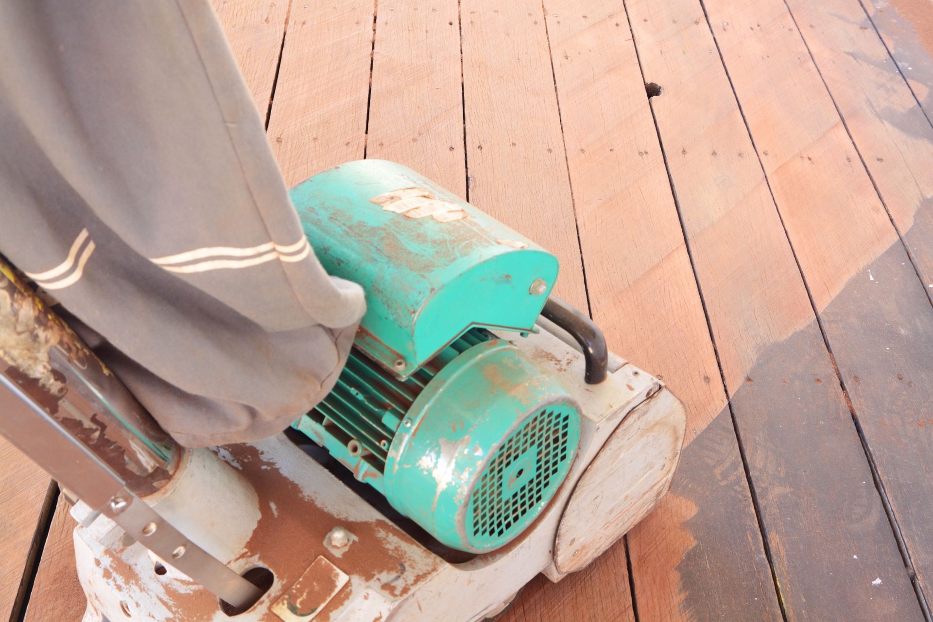 A person is using a machine to sand a wooden floor.