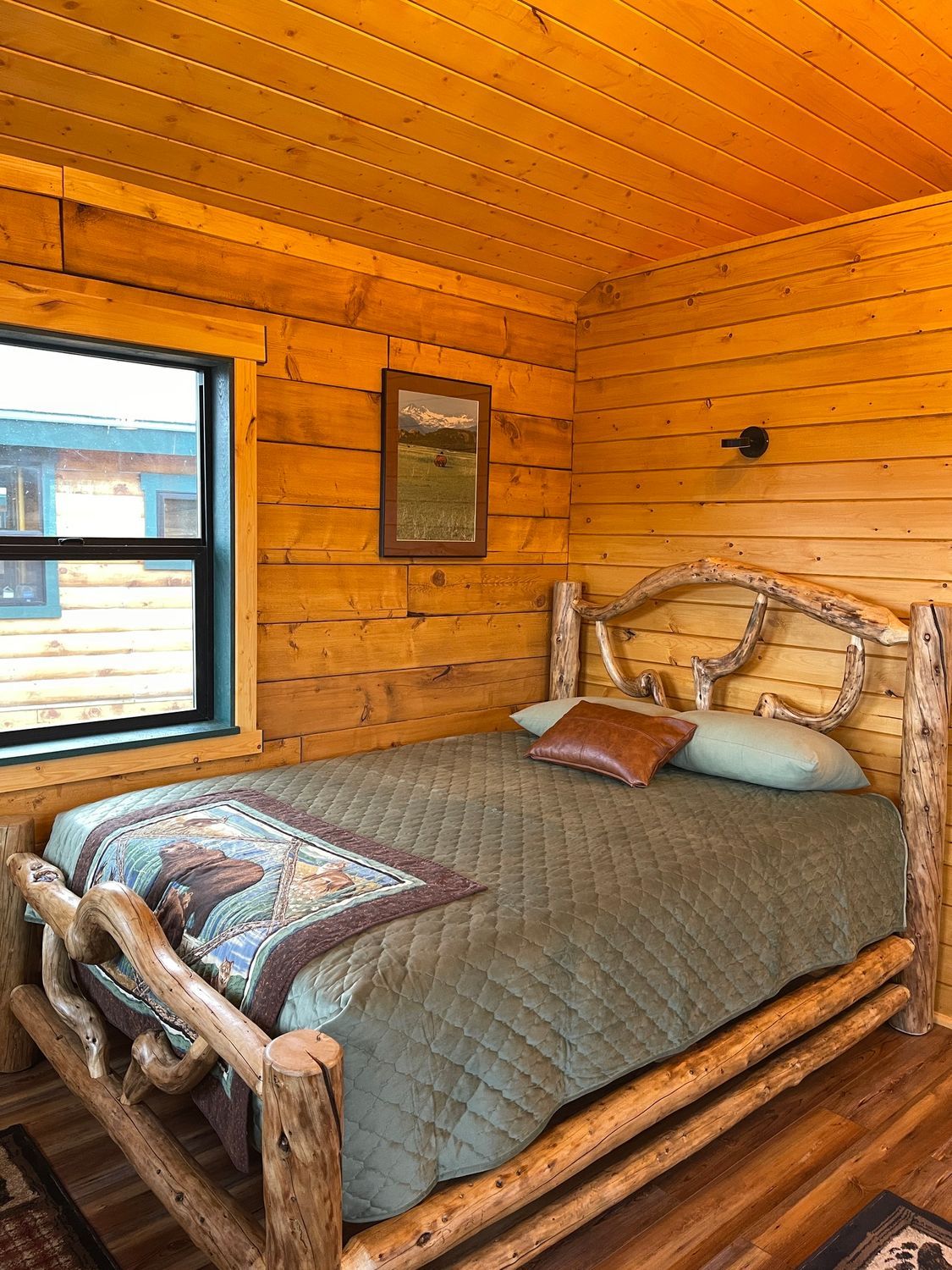 A bedroom in a log cabin with a log bed and a window.