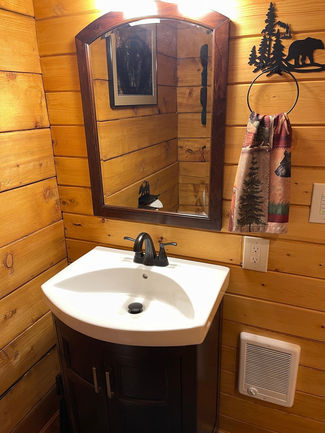 A bathroom with a sink , mirror and towel hanging on the wall.