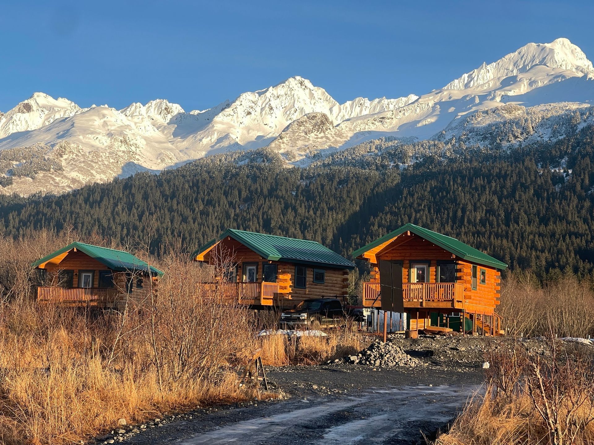 A row of log cabins with mountains in the background