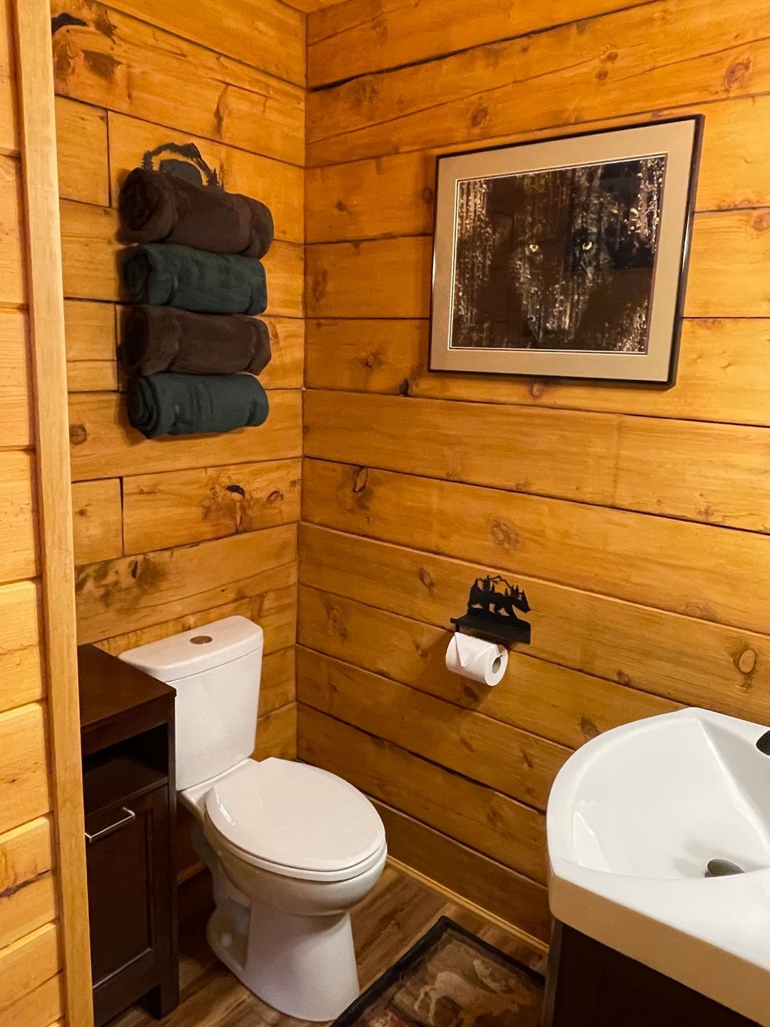 A bathroom with a toilet , sink , and picture on the wall.