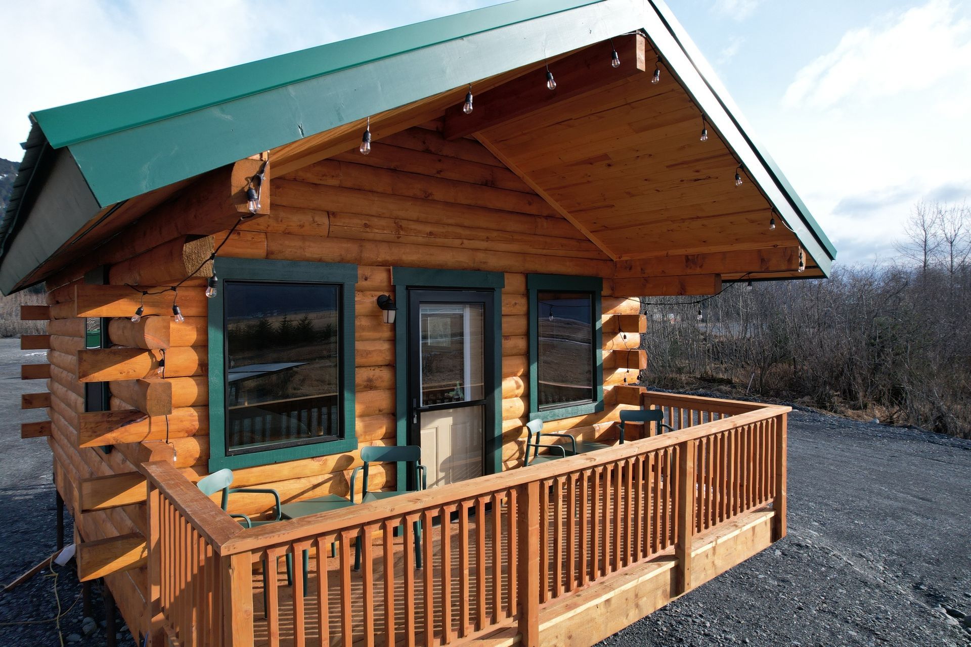 A small log cabin with a green roof and a balcony