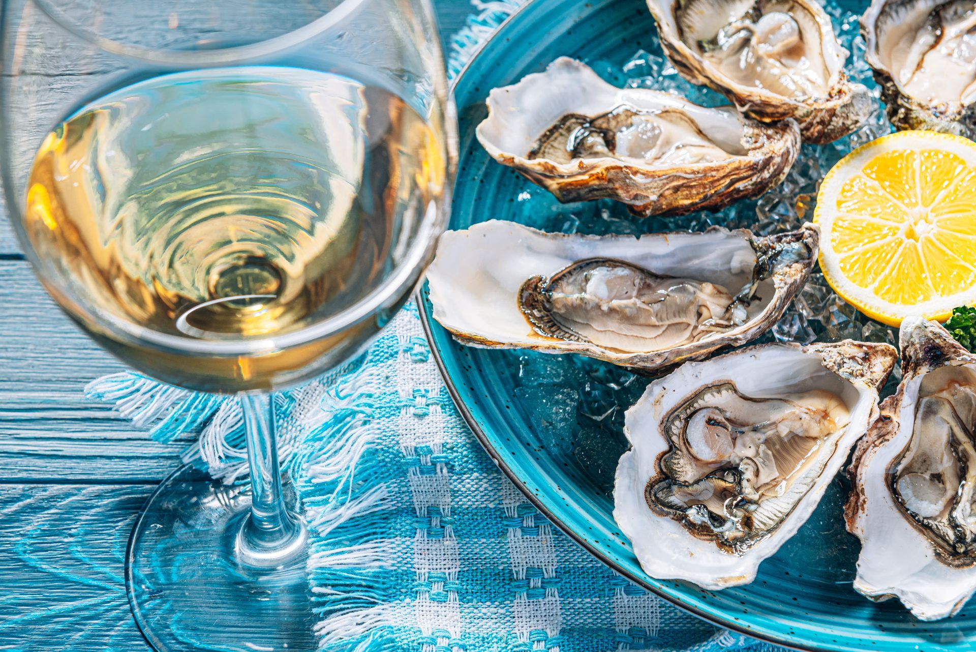 A plate of oysters and a glass of wine on a table.