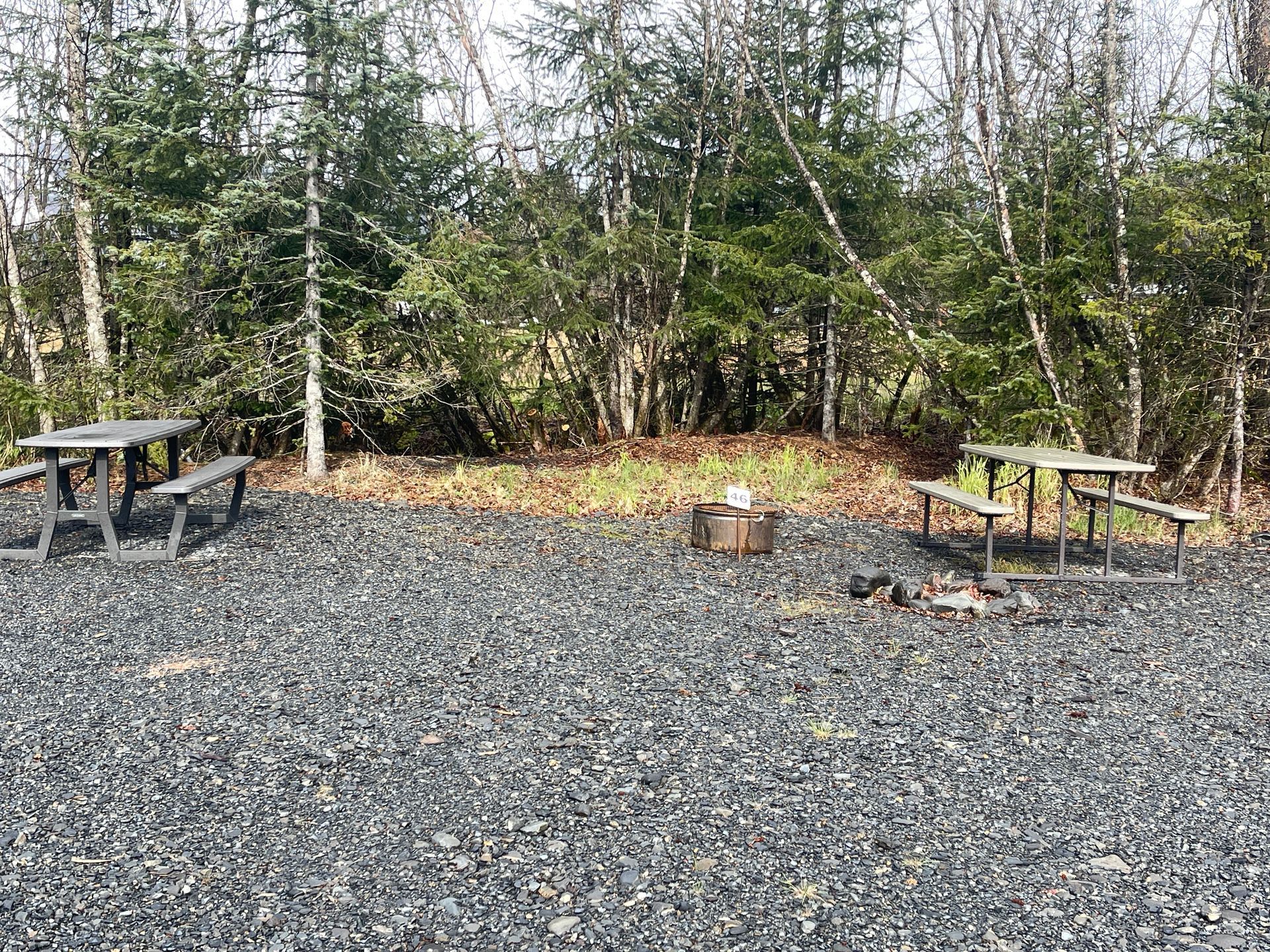 A jayco trailer is parked in a gravel lot with snowy mountains in the background.