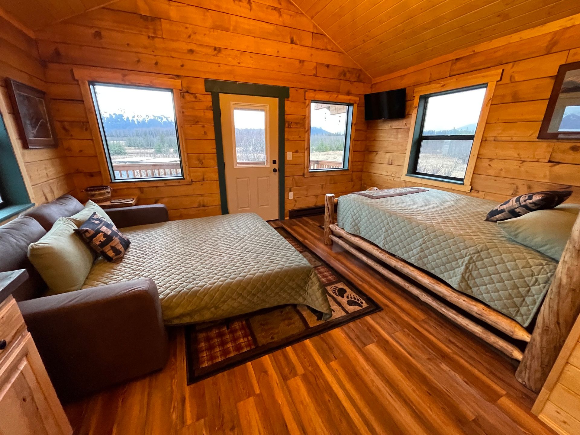 A bedroom in a log cabin with two beds and a couch.