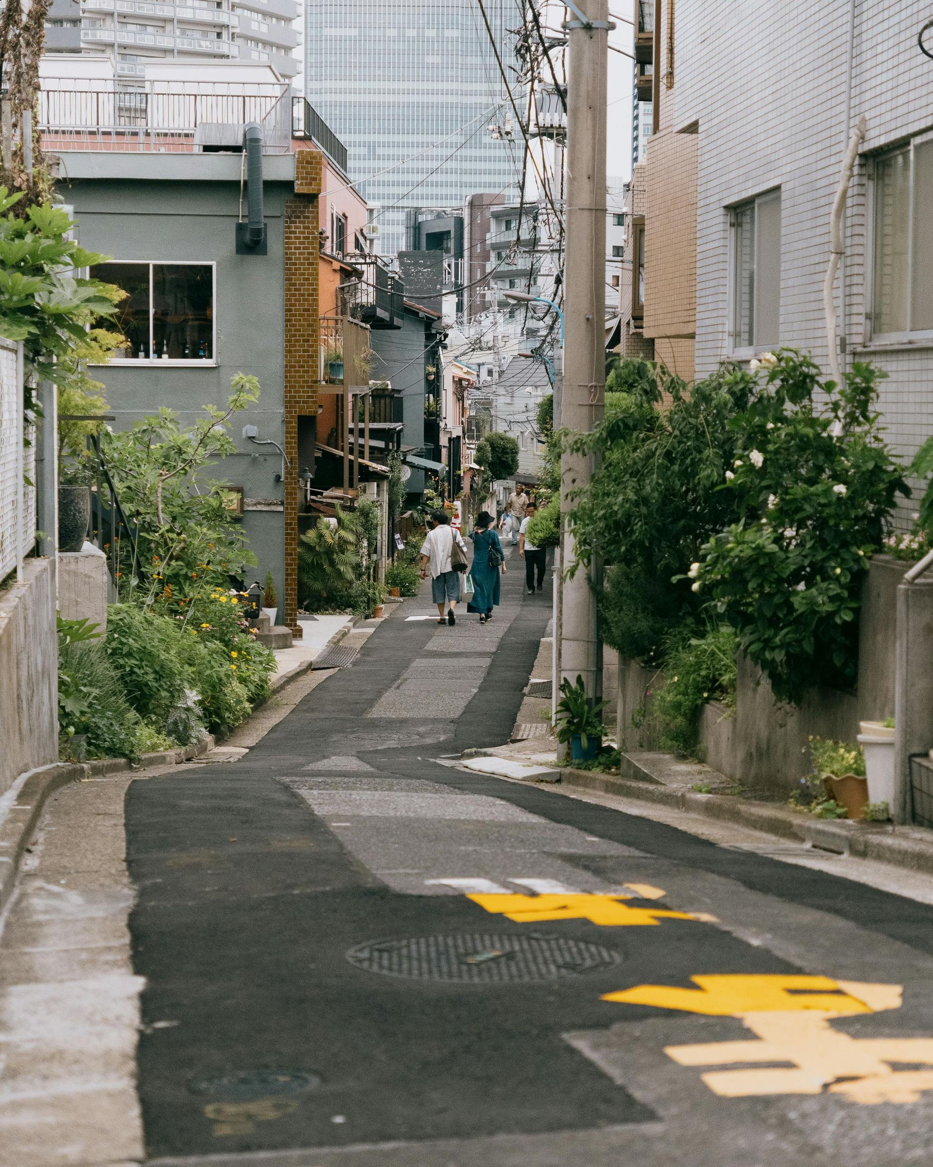 A couple of people are walking down a narrow street in a city.