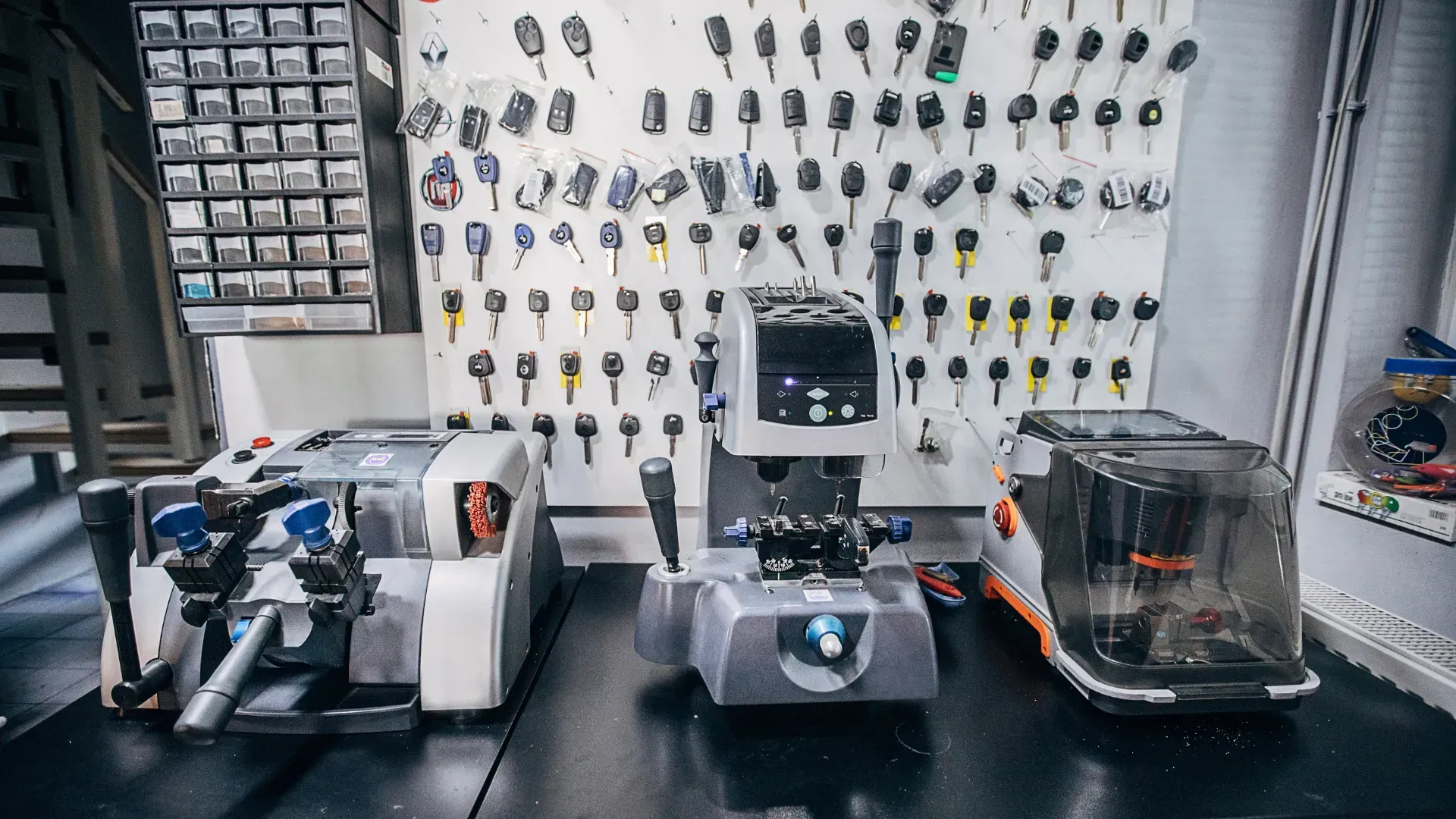 A machine is sitting on a table in front of a wall of keys.