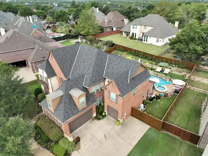 An aerial view of a large brick house in a residential area.