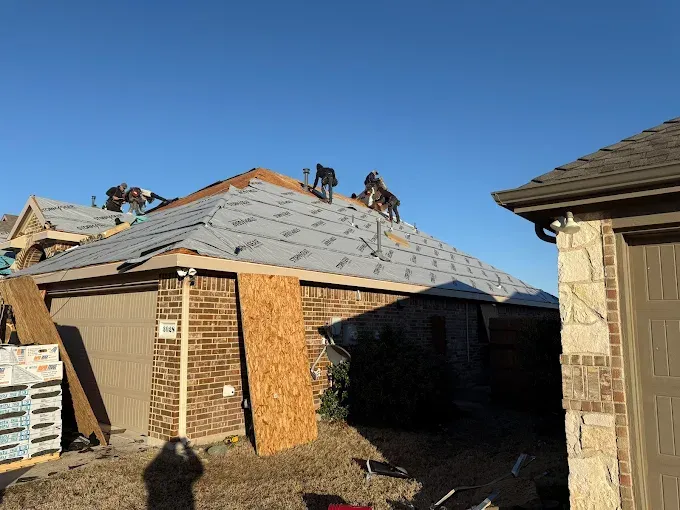 A group of people are working on the roof of a house.