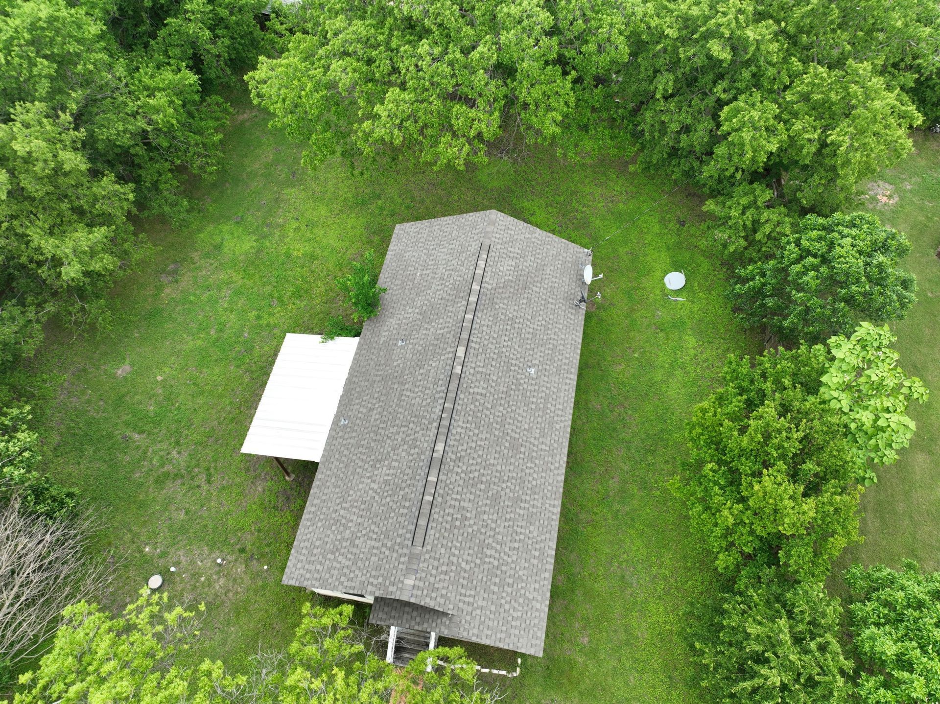 An aerial view of a house surrounded by trees and grass.