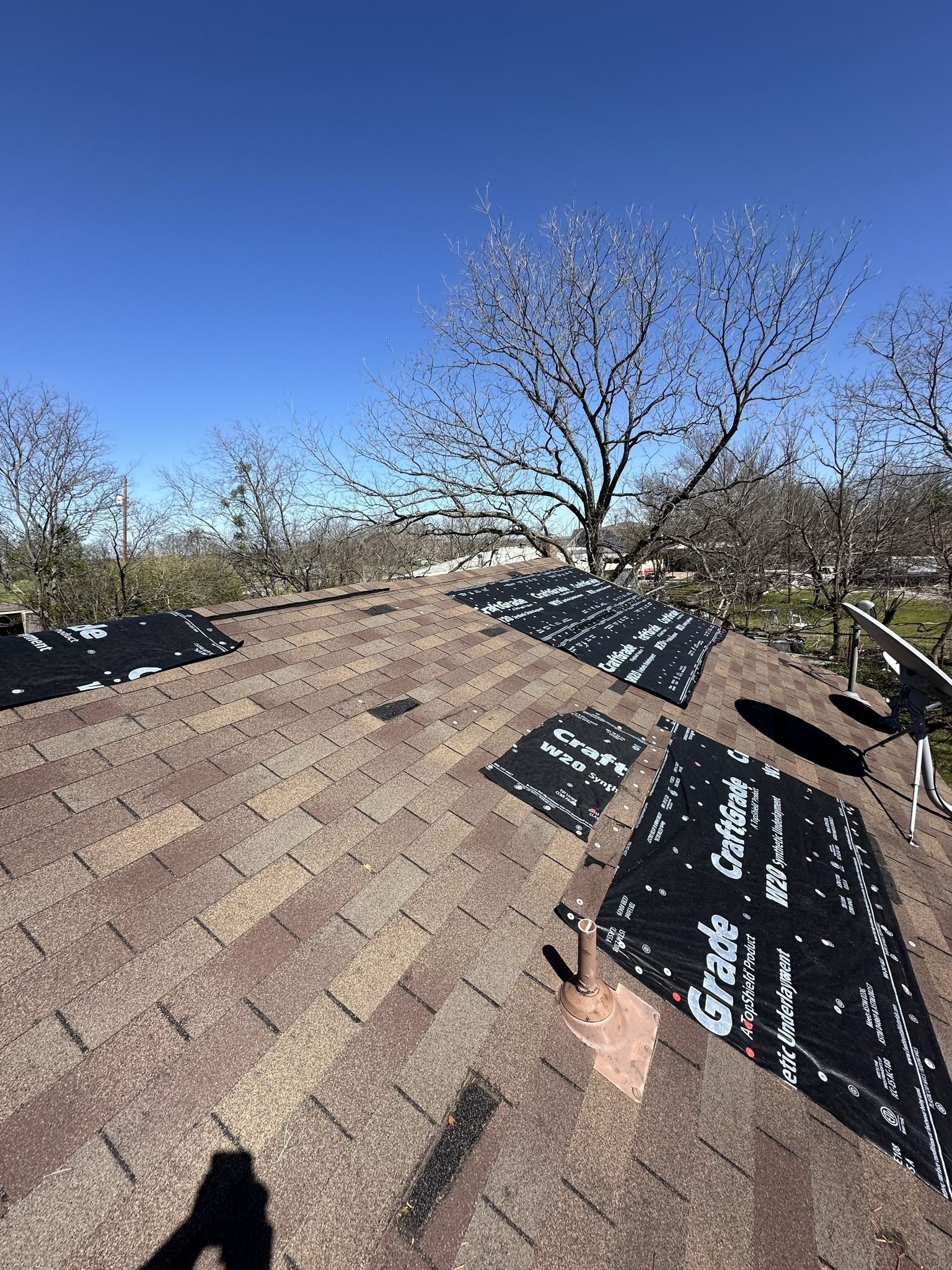 A roof with a lot of shingles on it and a tree in the background.