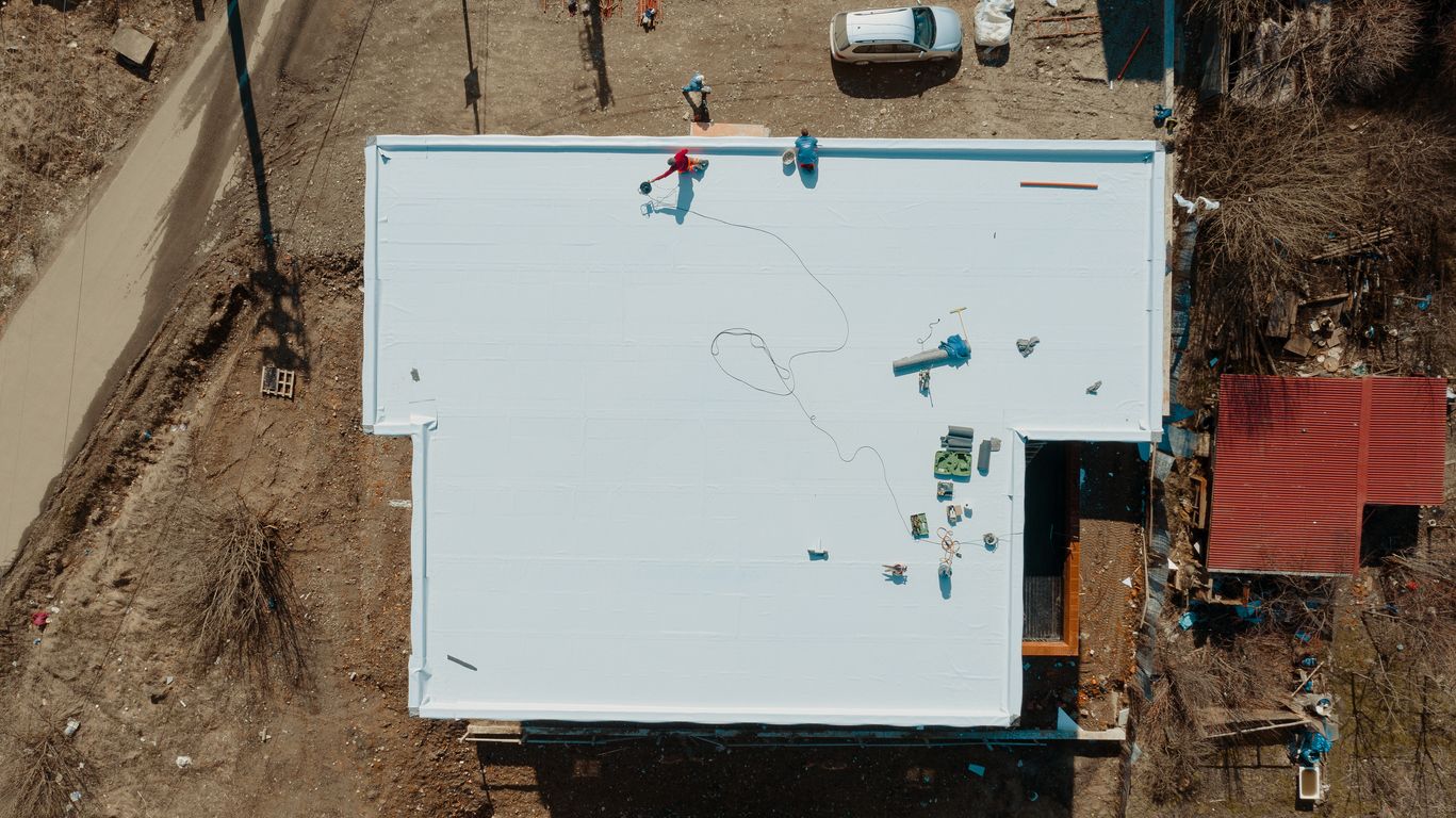 An aerial view of a building under construction with a white roof.