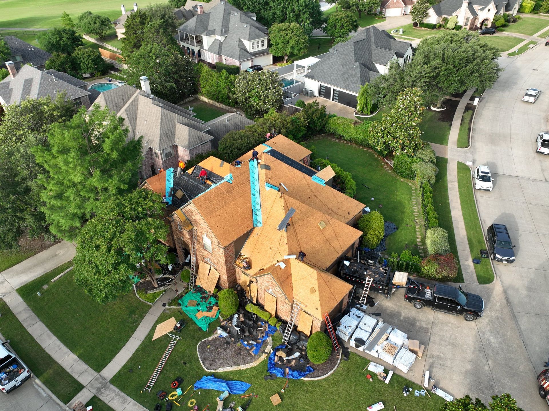 An aerial view of a house being roofed in a residential area.