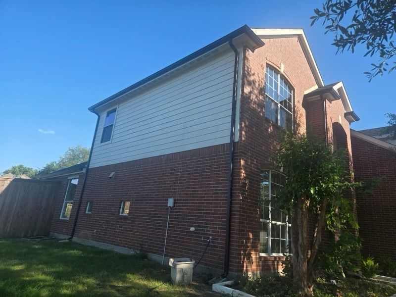 A large brick house with a white siding and a lot of windows.