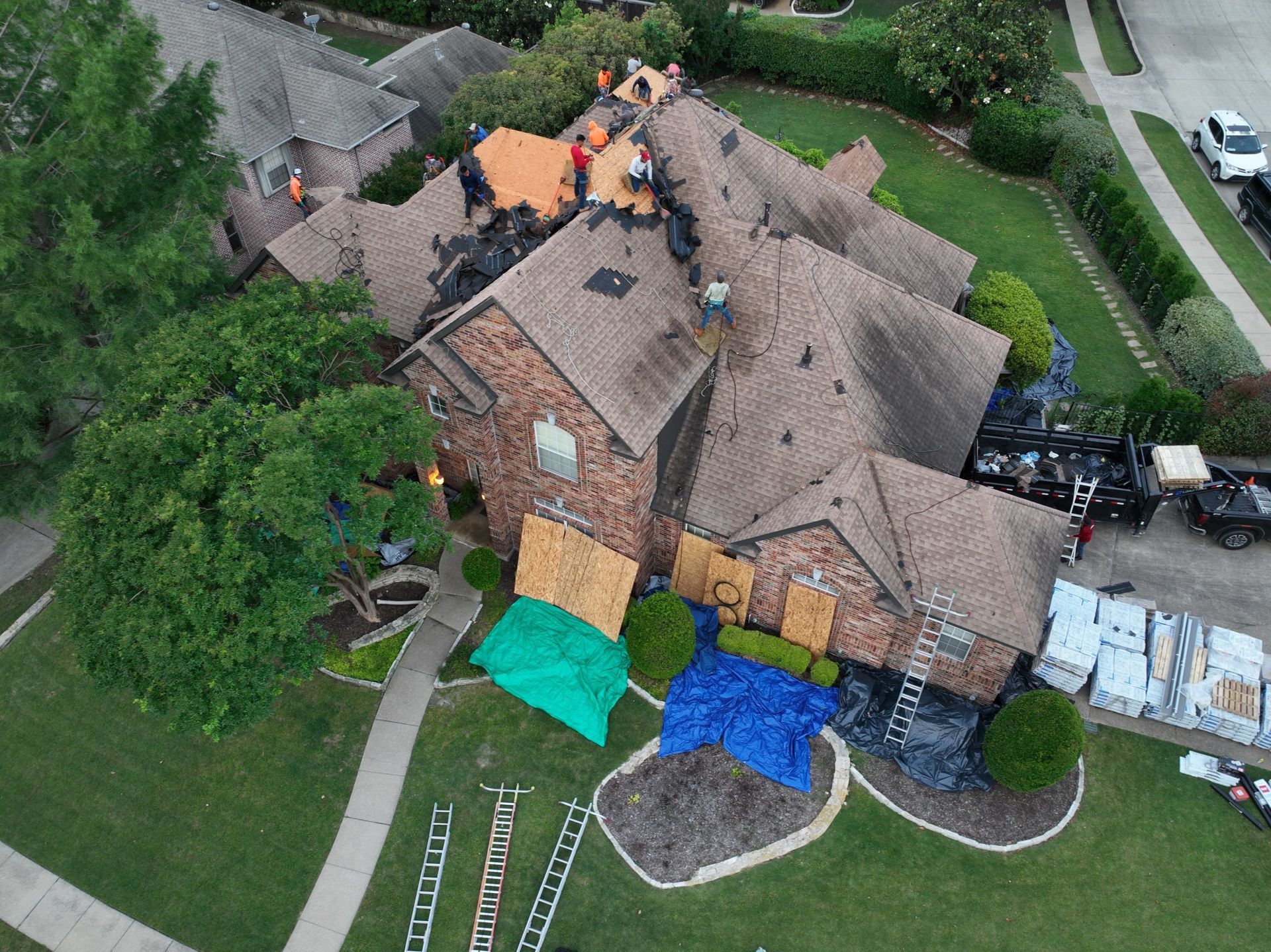 An aerial view of a house being remodeled with people working on the roof.