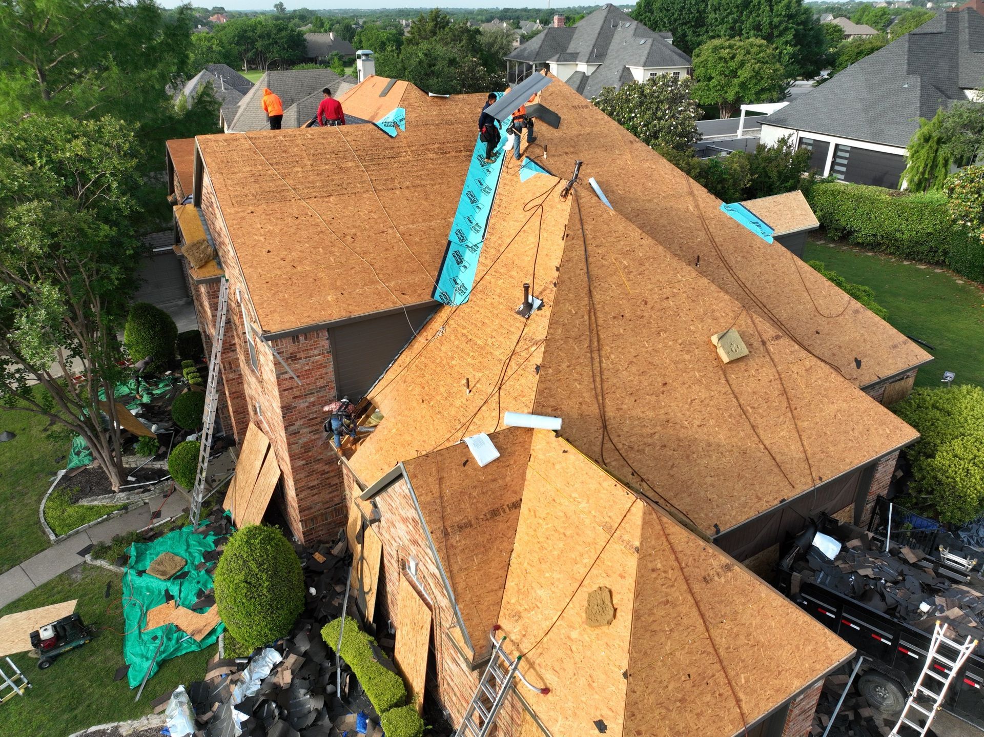 An aerial view of a large house with a roof being installed.