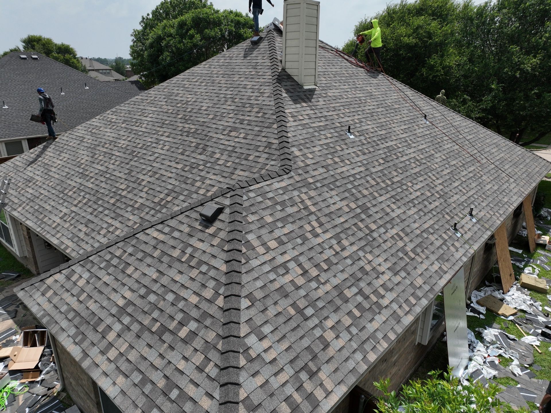 An aerial view of a house with a gray roof and a chimney.