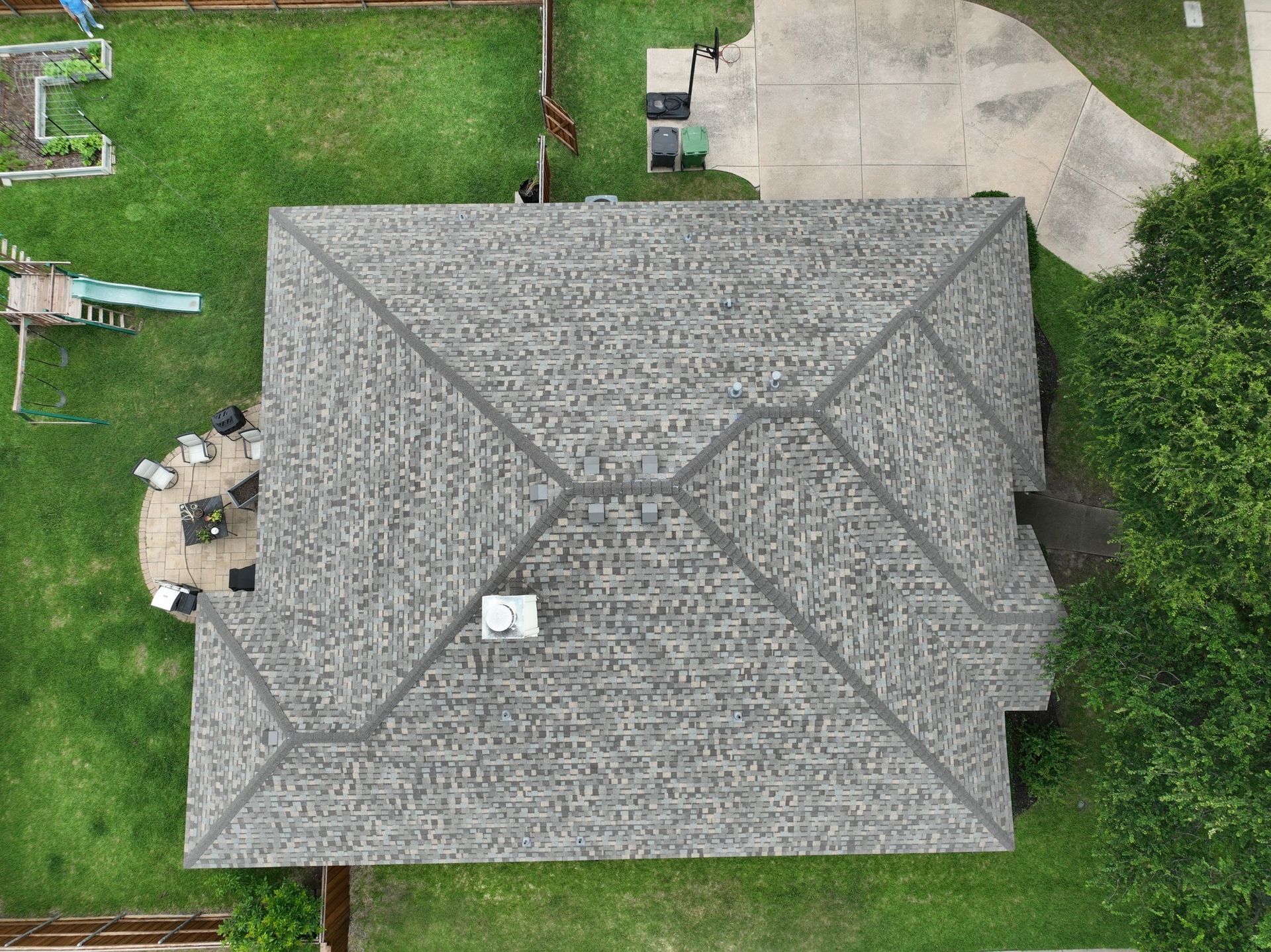 An aerial view of a house with a roof and a yard.