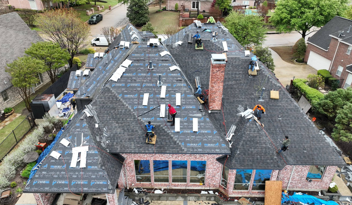 An aerial view of a roof being installed on a large house.