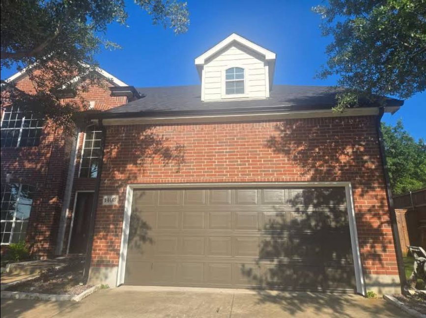 A brick house with a garage door and a white roof.