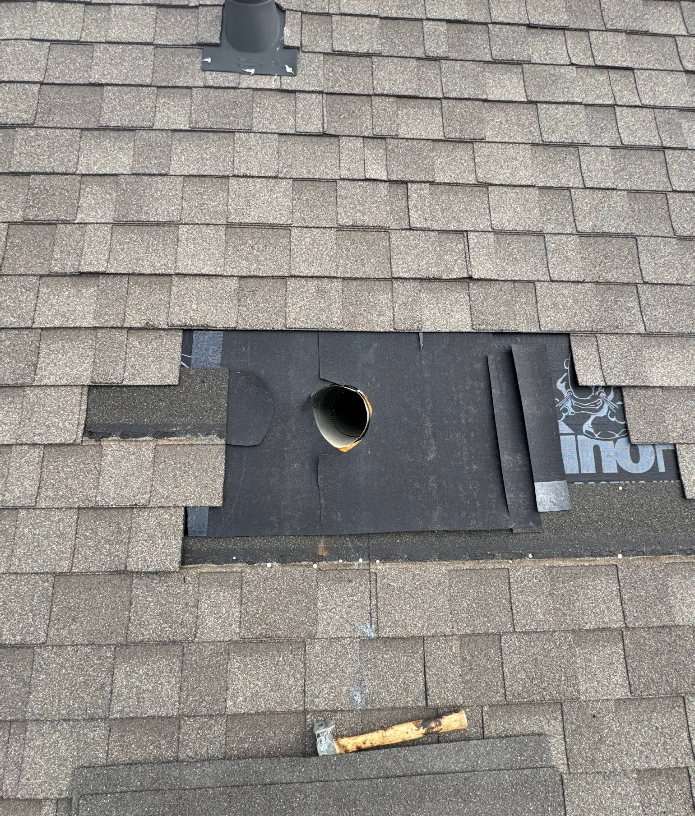 A roof with a hole in it and a hammer on the ground