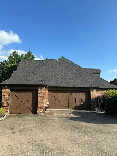 A house with two garage doors and a black roof.