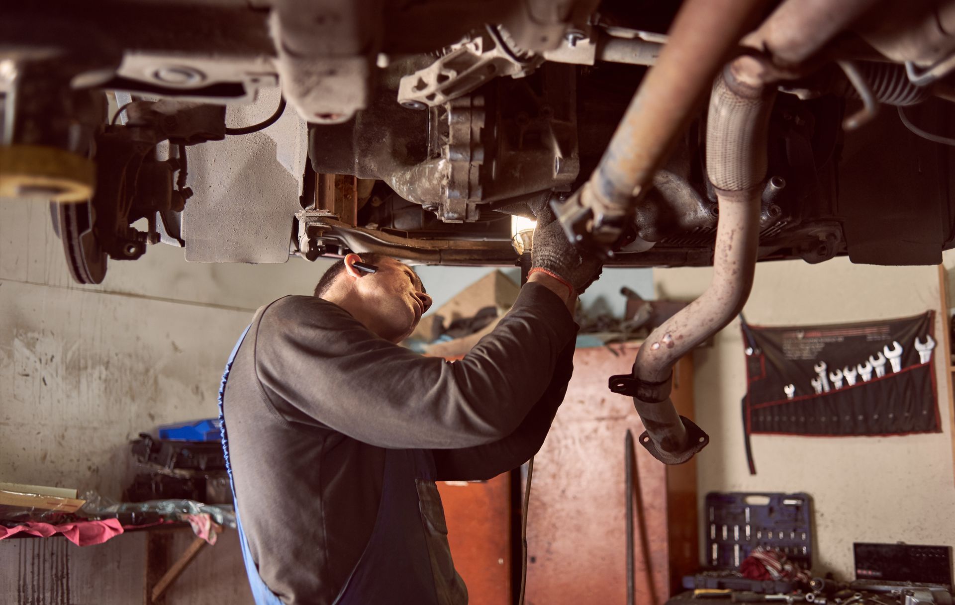 A man is working under a car in a garage.