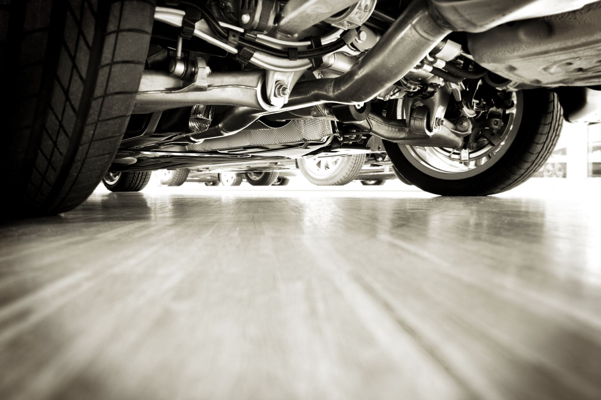 A black and white photo of the underside of a car in a garage.