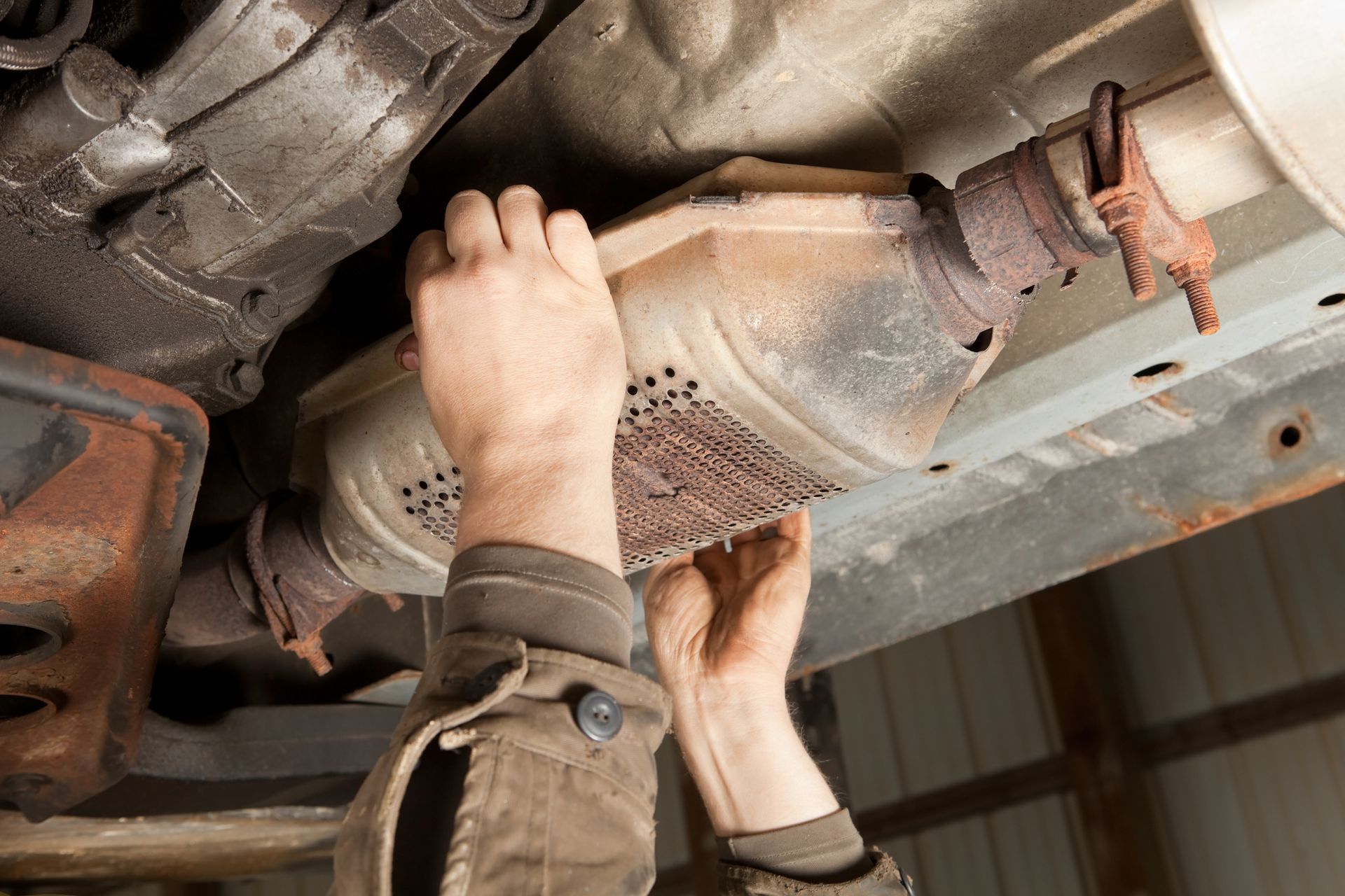 A person is working on the exhaust pipe of a car.