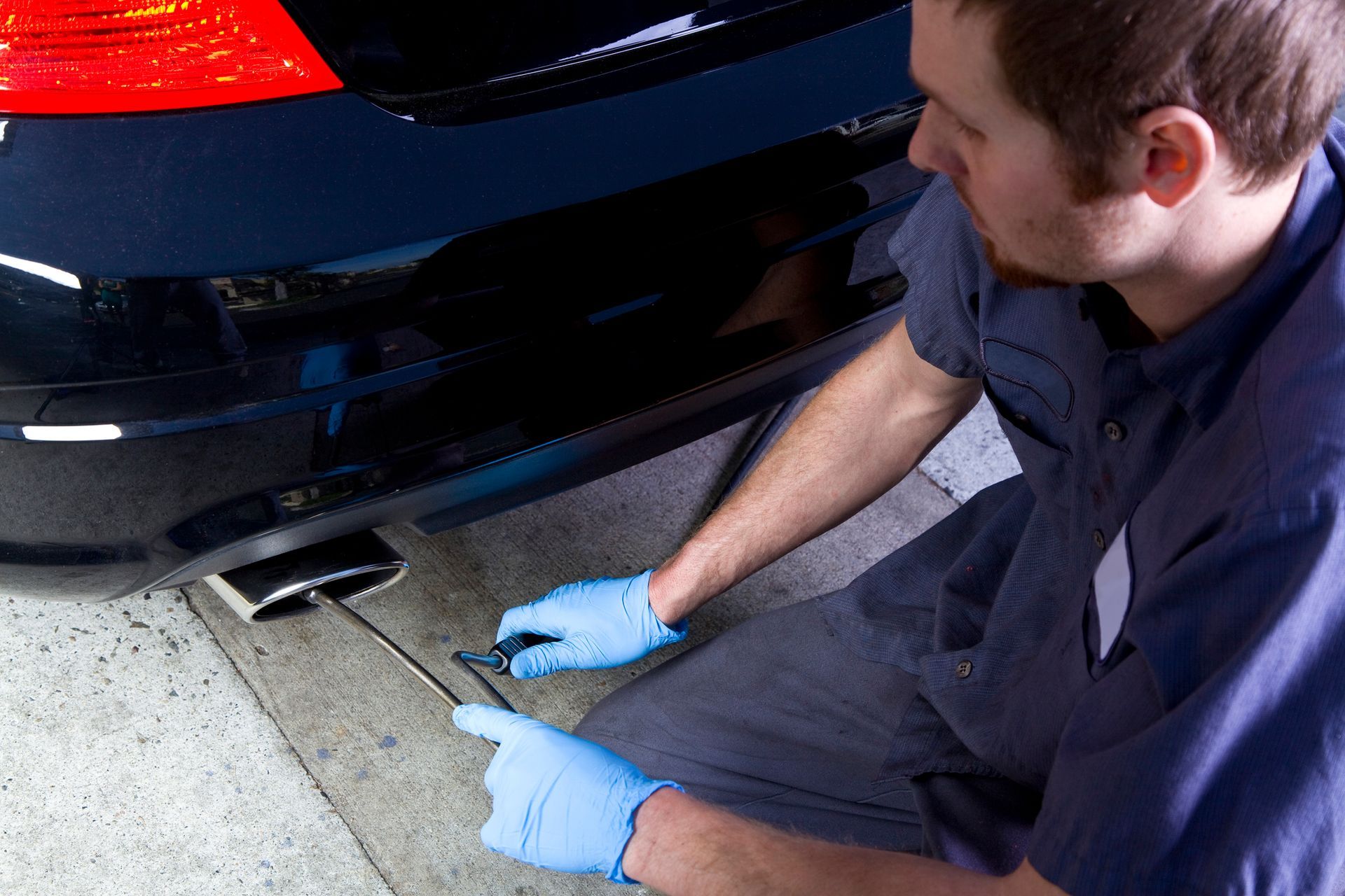 A man wearing blue gloves is working on a car