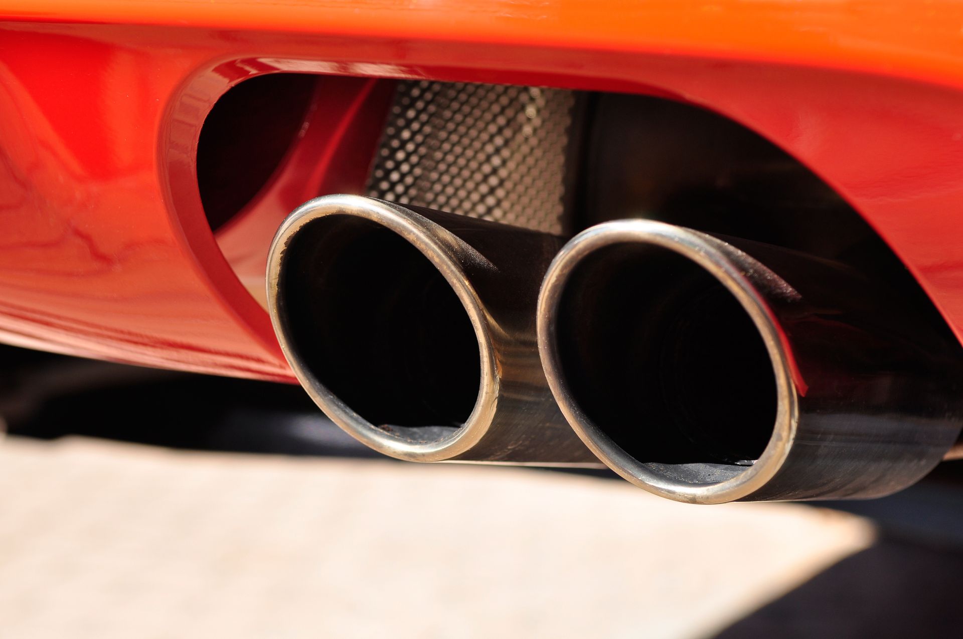 A close up of a red car 's exhaust pipes