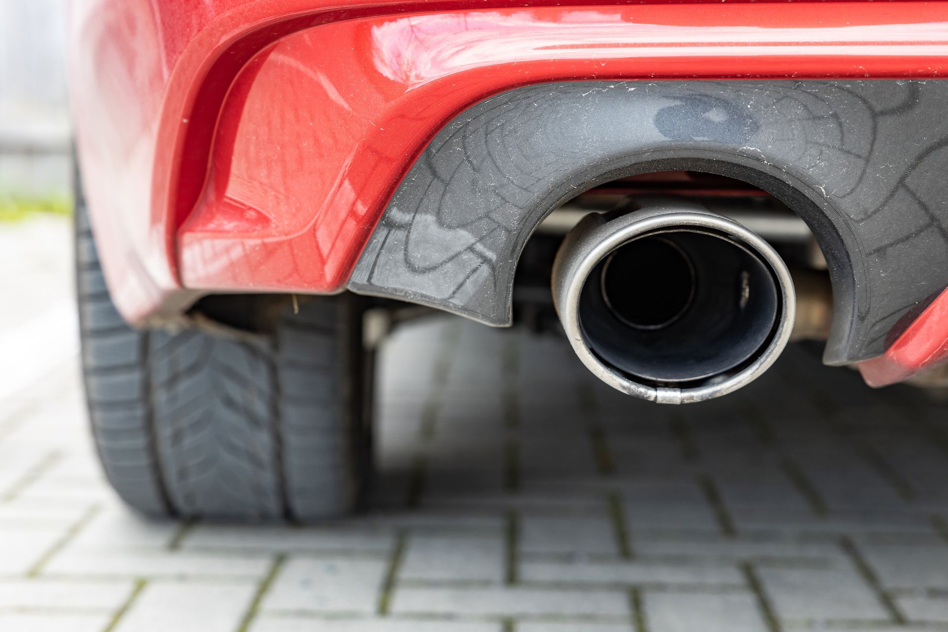 A close up of the exhaust pipe of a red car.