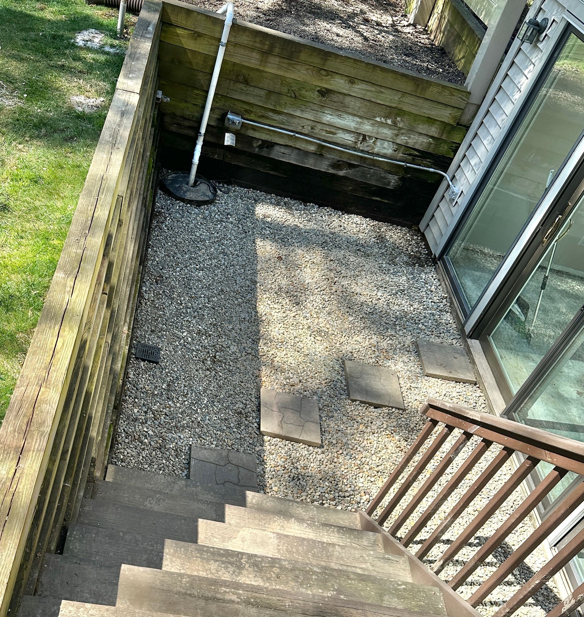 Drainage correction project using clean Michigan stone to improve water flow near foundation in East Lansing, Michigan