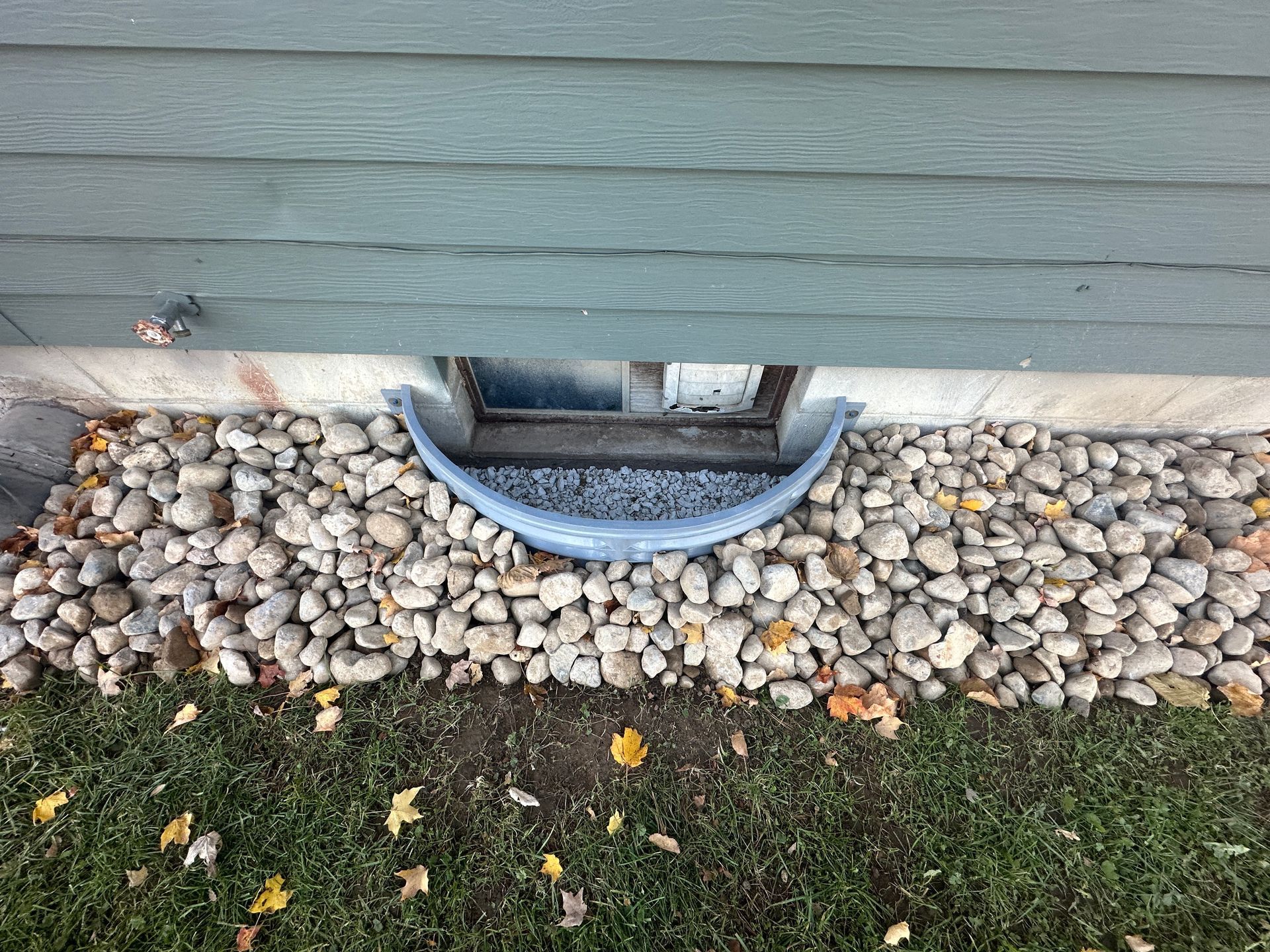 Basement window well installed with clean drainage stone to improve water drainage around the foundation in Mason, Michigan
