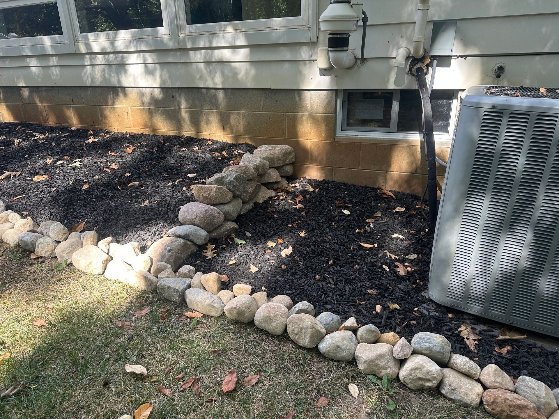 Boulder retaining wall installation with stone edging and regraded landscape bed in Okemos, Michigan
