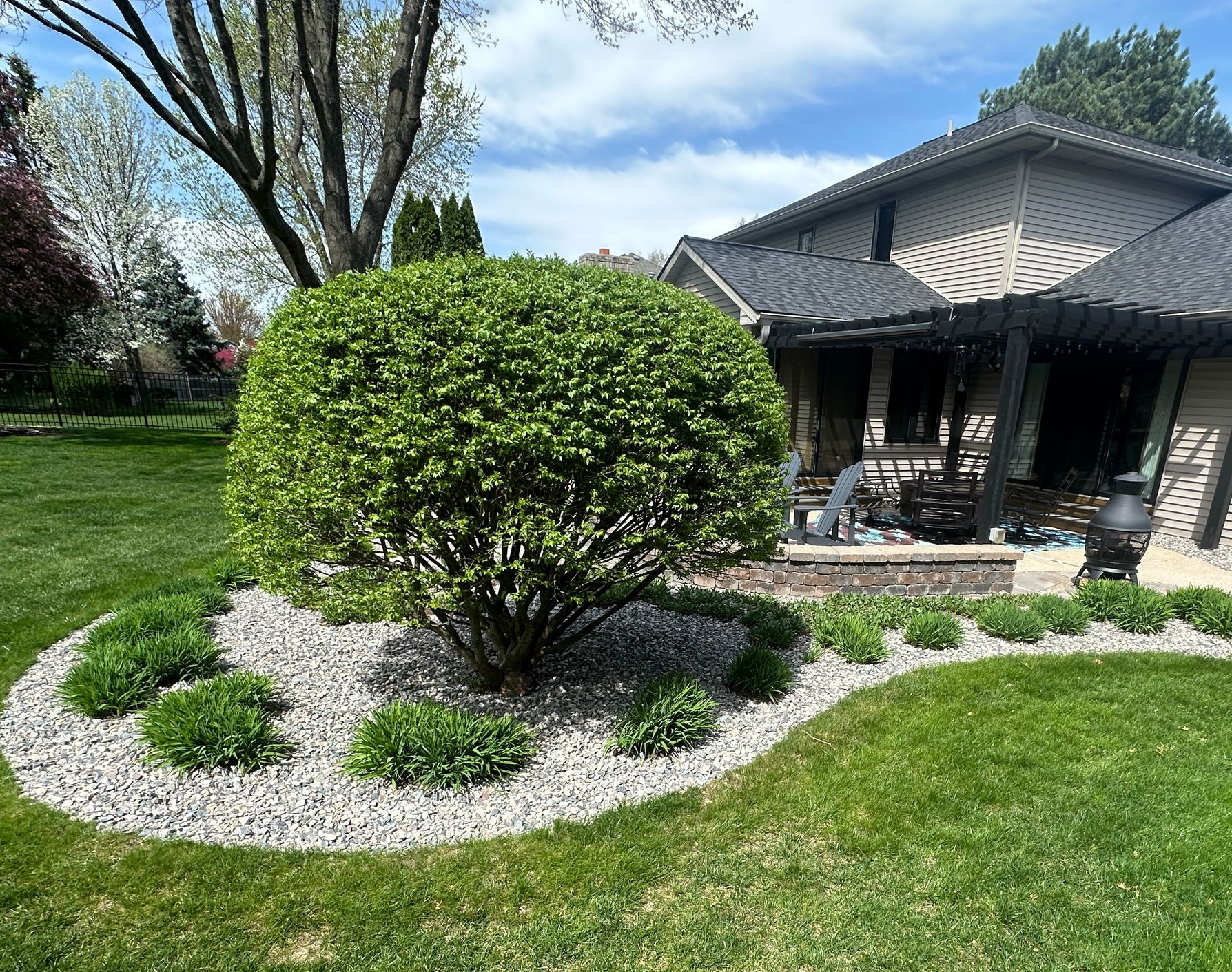 Shrub trimming and landscape bed renovation with decorative stone mulch in East Lansing, Michigan