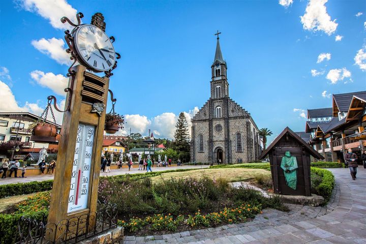 Um relógio e um termômetro estão em frente a uma igreja.