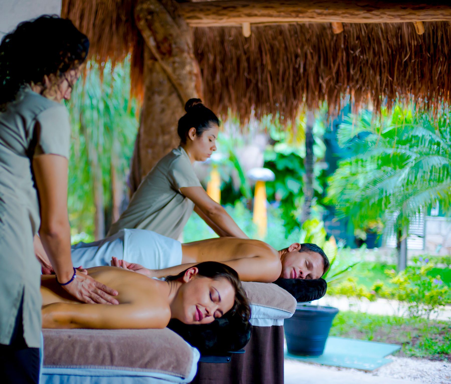 Couple relaxing in a wooden sauna, holding hands. Woman reclines, eyes closed, wearing a white bikini. 