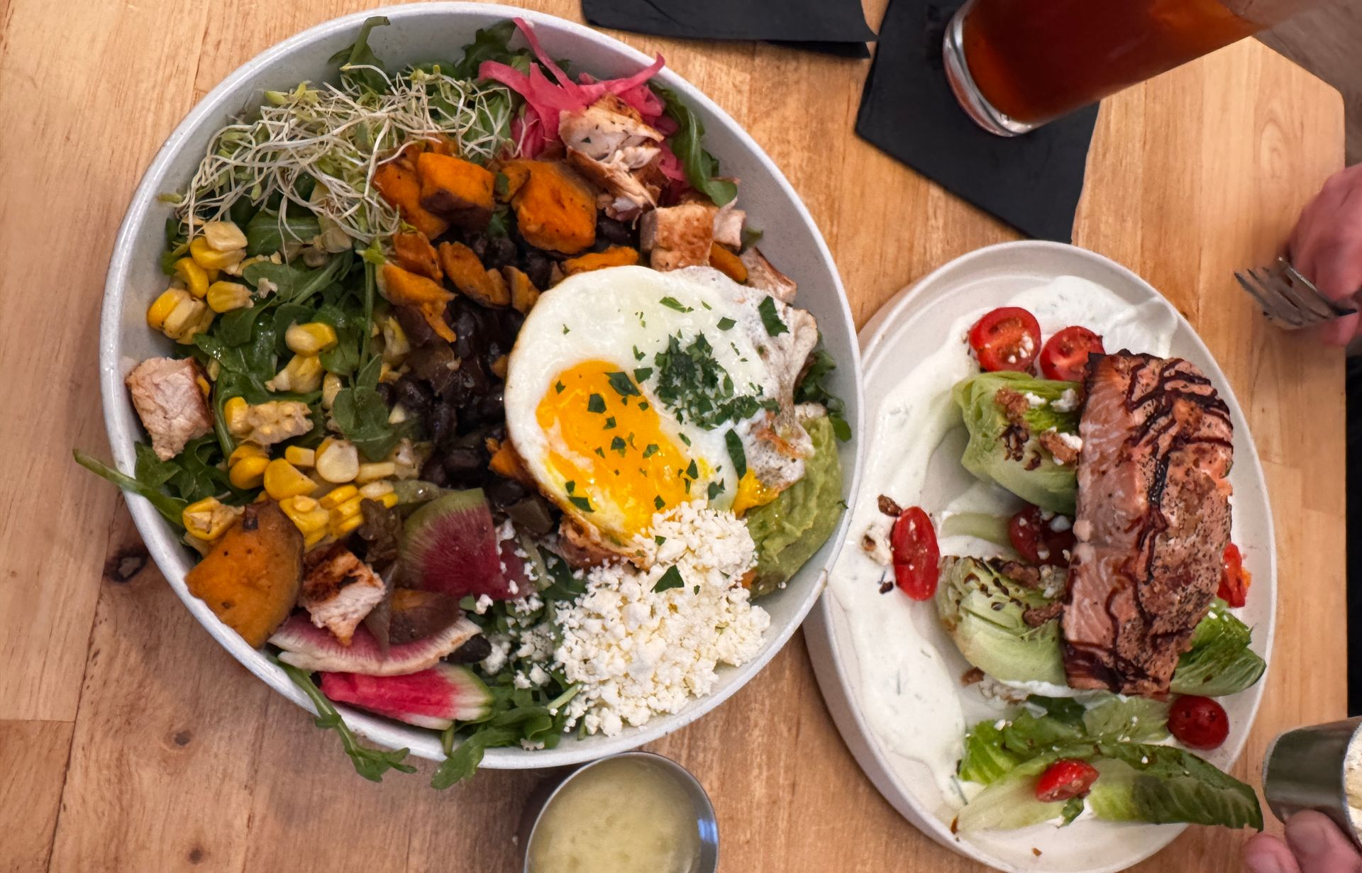 Two men at counter; one pours powder from a bag, other looks on, coffee cup nearby. Gym setting.