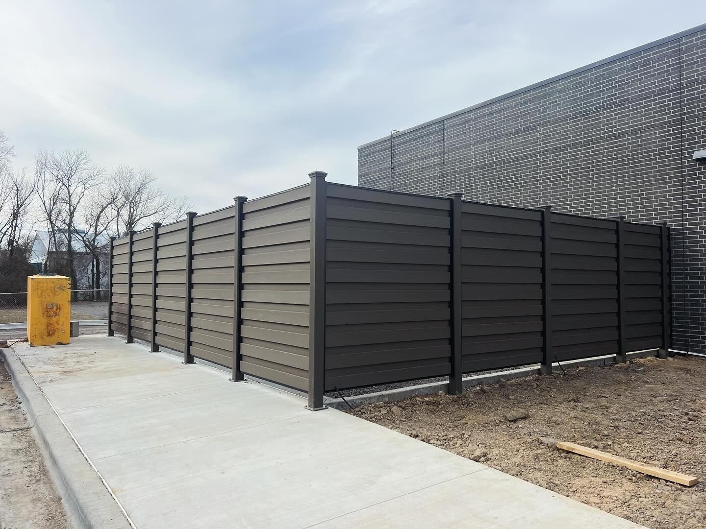 A black fence is sitting next to a sidewalk in front of a building.