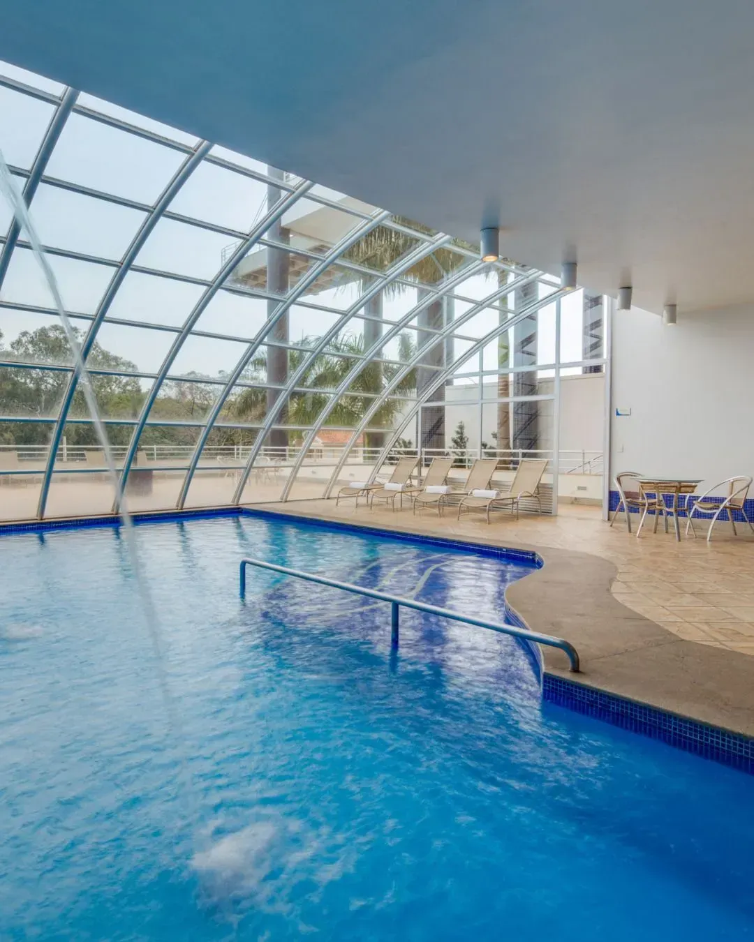 Arranha-céu alto iluminado à noite, com um restaurante no terraço e luzes da cidade ao redor.