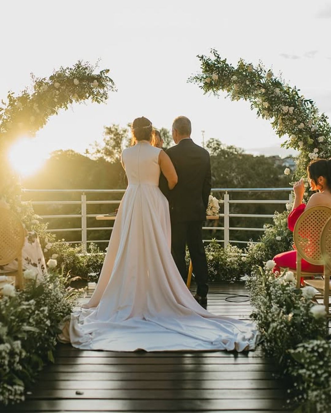Cena romântica de quarto com bandeja de café da manhã, travesseiros vermelhos e pétalas de rosa na cama.