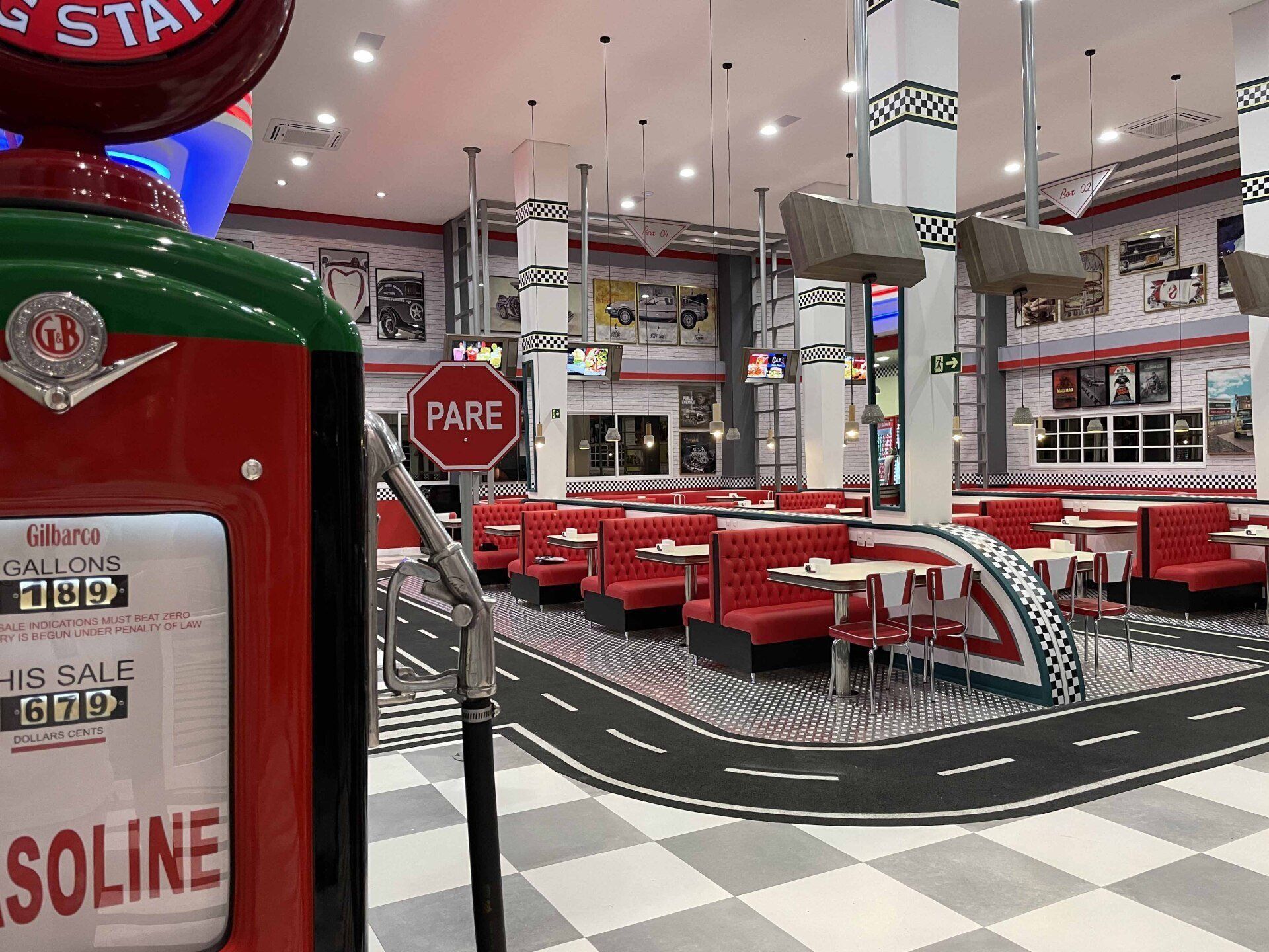 Interior retrô de restaurante com cabines vermelhas, piso xadrez e bomba de gasolina. Design de rua no chão.